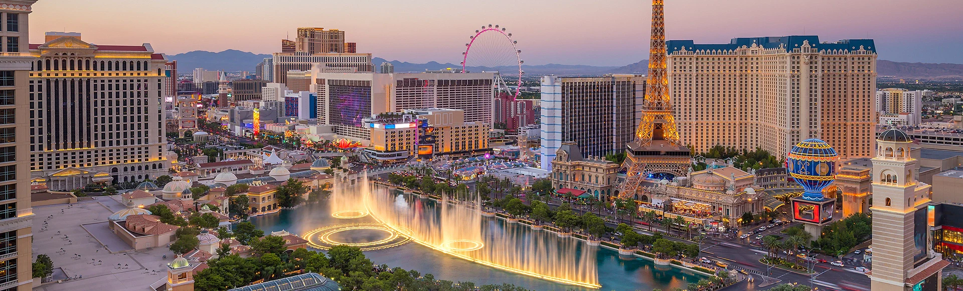 Panoramic view of the Las Vegas Strip at dusk, featuring the Bellagio fountains, Eiffel Tower replica, and High Roller Ferris wheel.